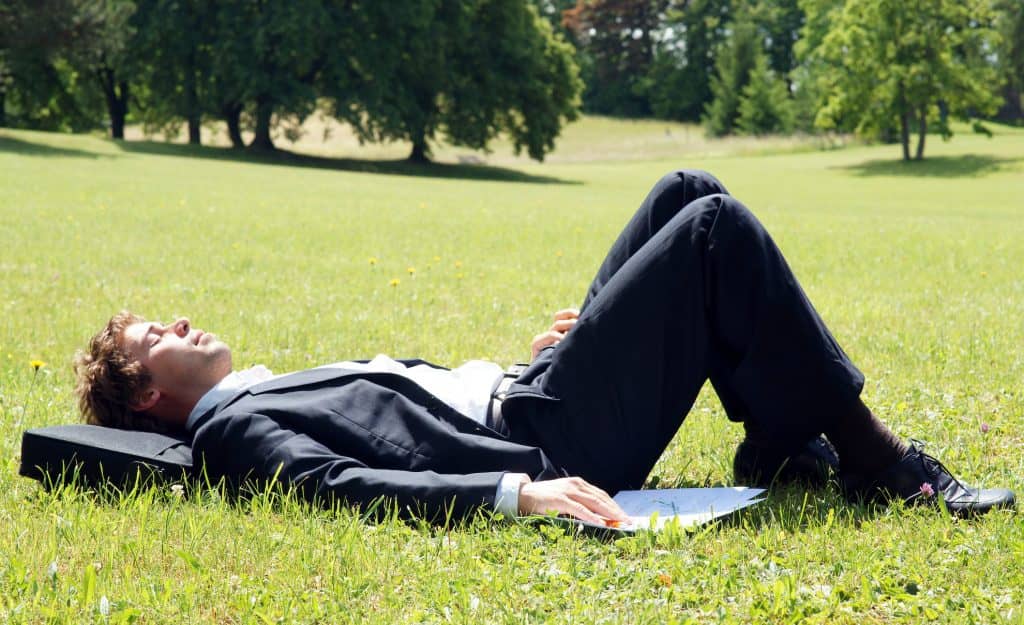 Um homem de terno relaxa na grama.