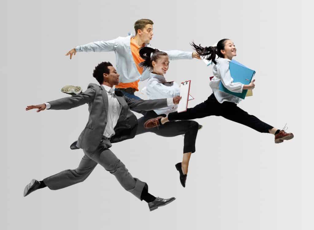 A group of business people enjoy fun and paediatric osteopathy by playfully jumping in the air.