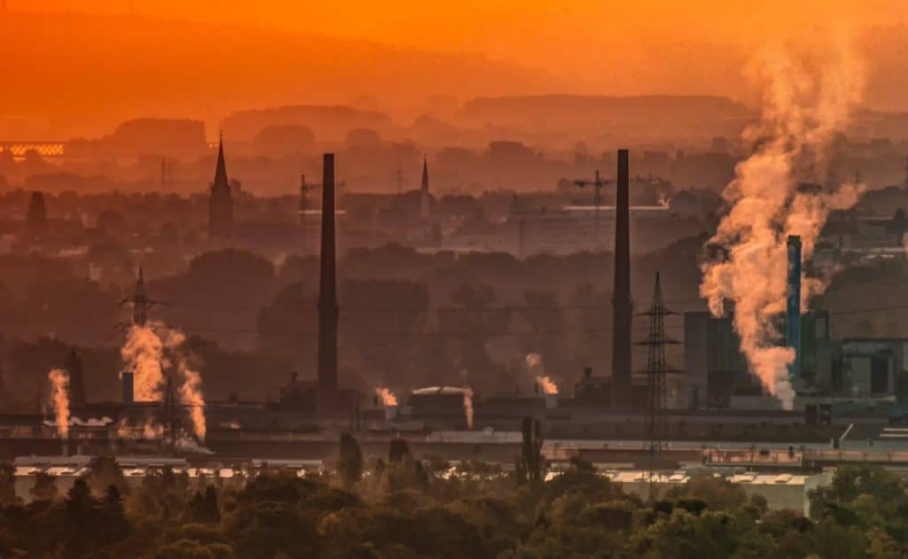 A factory at sunset, emitting smoke at dusk.