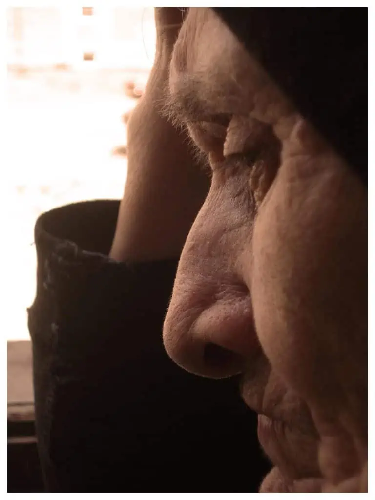 Eine ältere Frau blickt aus einem Fenster.