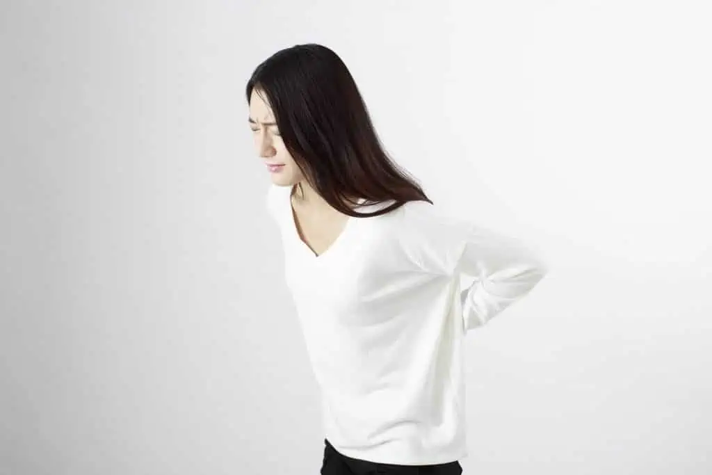 Eine Frau steht mit in die Hüften gestemmten Händen bei einer sportosteopathischen Behandlung in Hamburg.