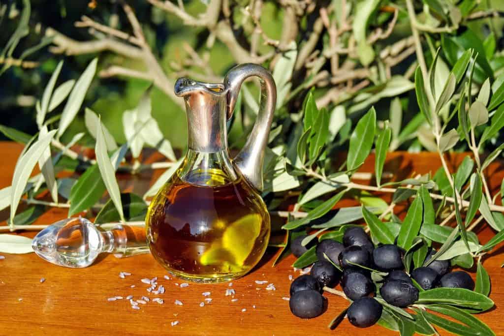 La descrizione mostra un tavolo di legno rustico adornato con la ricca essenza dell'olio d'oliva e il fascino delle olive nere.
