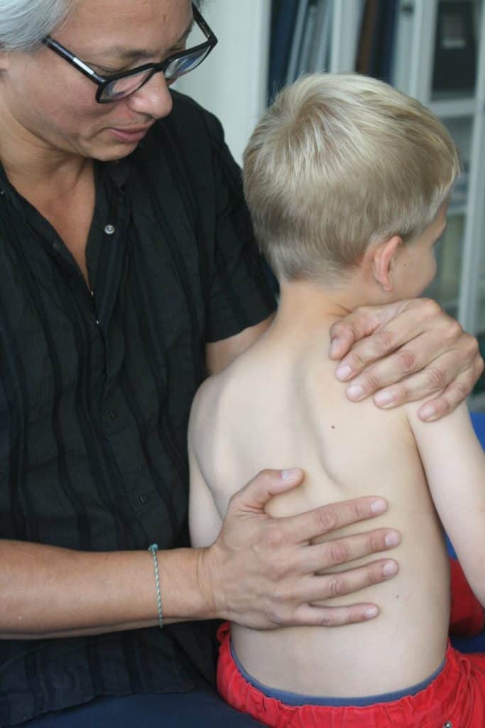 Eine Hamburger Osteopathie-Praktizierende hält einem Kind sanft den Rücken.
