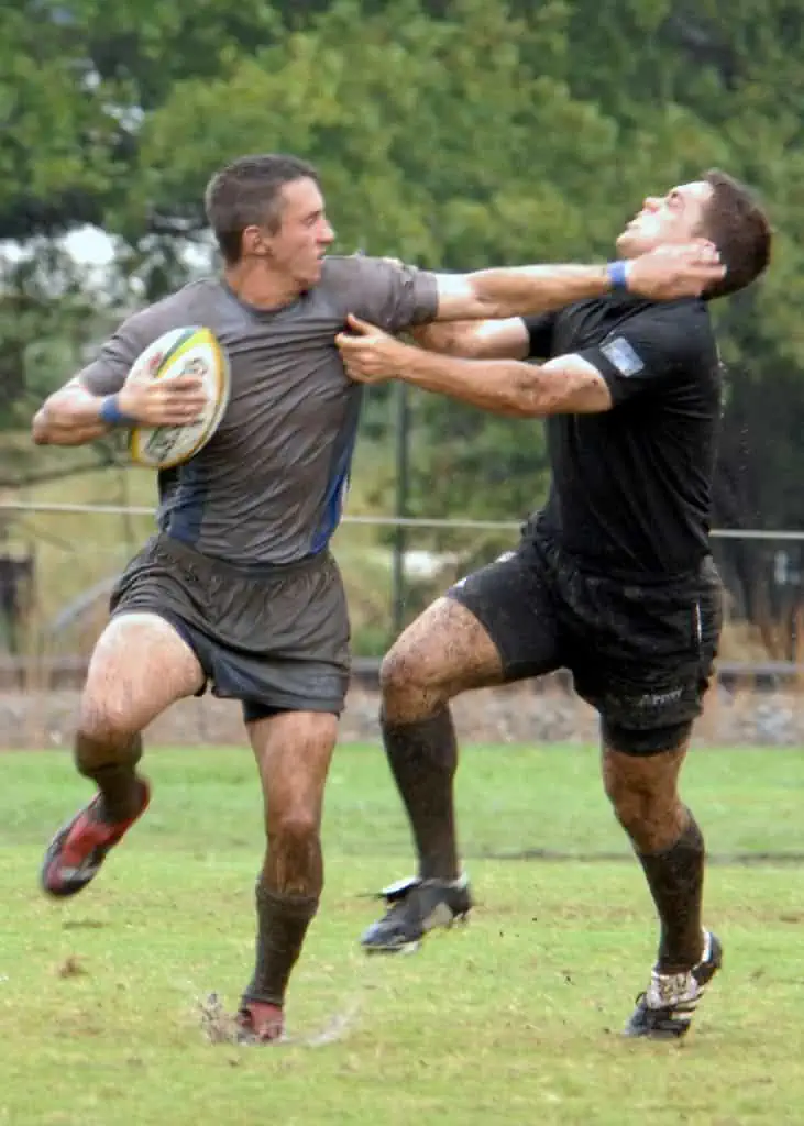 Zwei Rugbyspieler wetteifern auf einem Feld um den Ballbesitz.