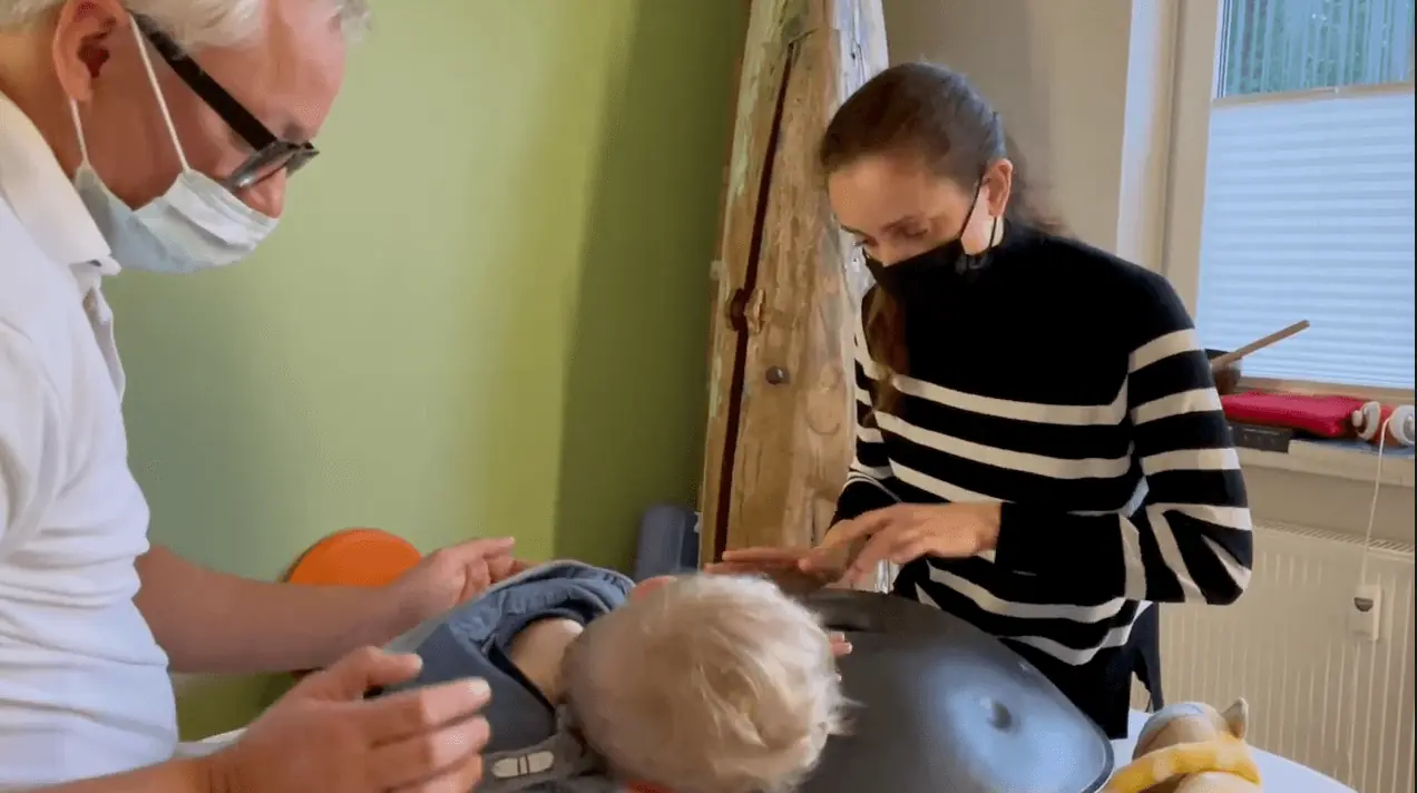 Eine Frau mit Maske kümmert sich in Hamburg um ein Baby auf einem Tisch.