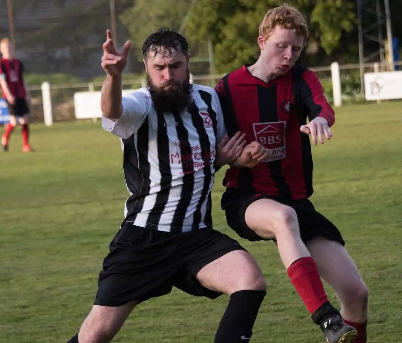 Zwei Männer spielen Fußball auf einem Feld und werden in Hamburg osteopathisch behandelt.