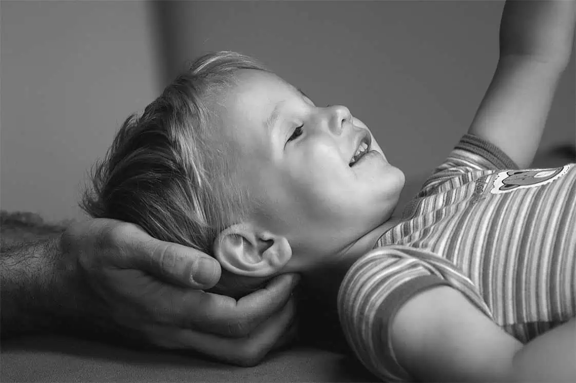 Schwarz-Weiß-Foto eines Kindes mit der Hand auf dem Kopf, das Unschuld und Verletzlichkeit darstellt.