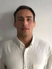 Ein Mann in einem weißen Hemd steht an einer Wand und erhält eine Osteopathie-Hamburg-Behandlung.