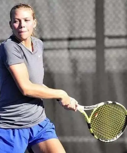 Eine Tennisspielerin übt ihren Schwung mit einem Schläger und integriert dabei sportosteopathische Techniken.