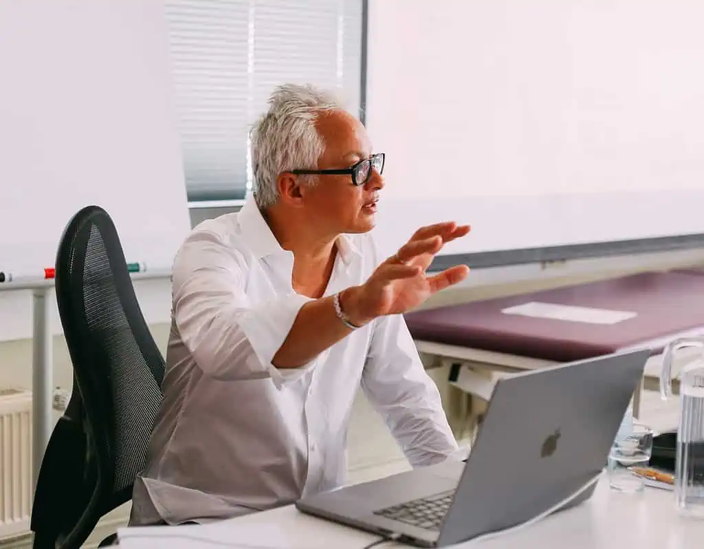 Ein Mann sitzt an einem Schreibtisch mit einem Laptop vor sich und arbeitet an seinem Osteopathie-Hamburger Geschäft.