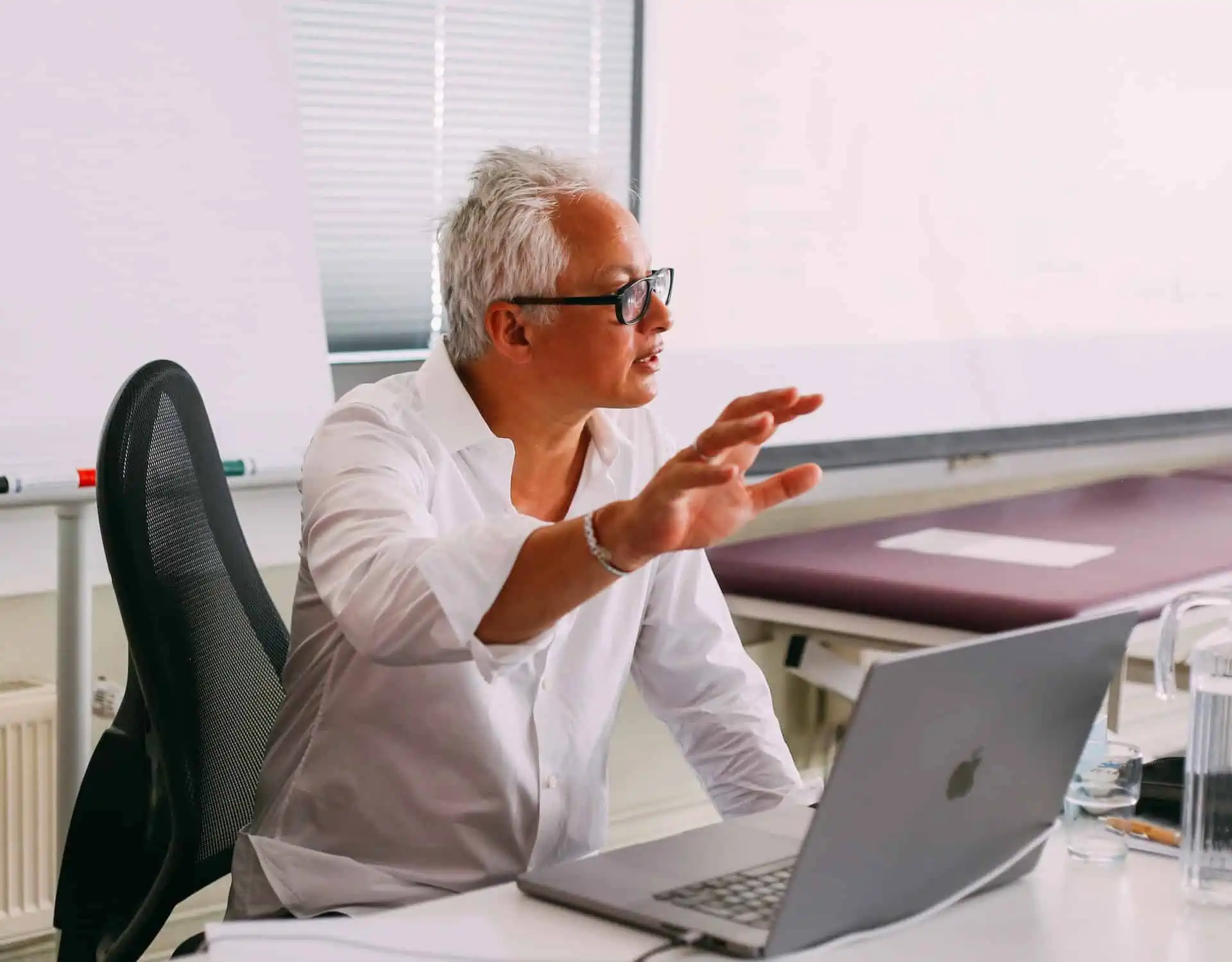 Ein Mann sitzt an einem Schreibtisch mit einem Laptop vor sich und arbeitet an seinem Osteopathie-Hamburger Geschäft.