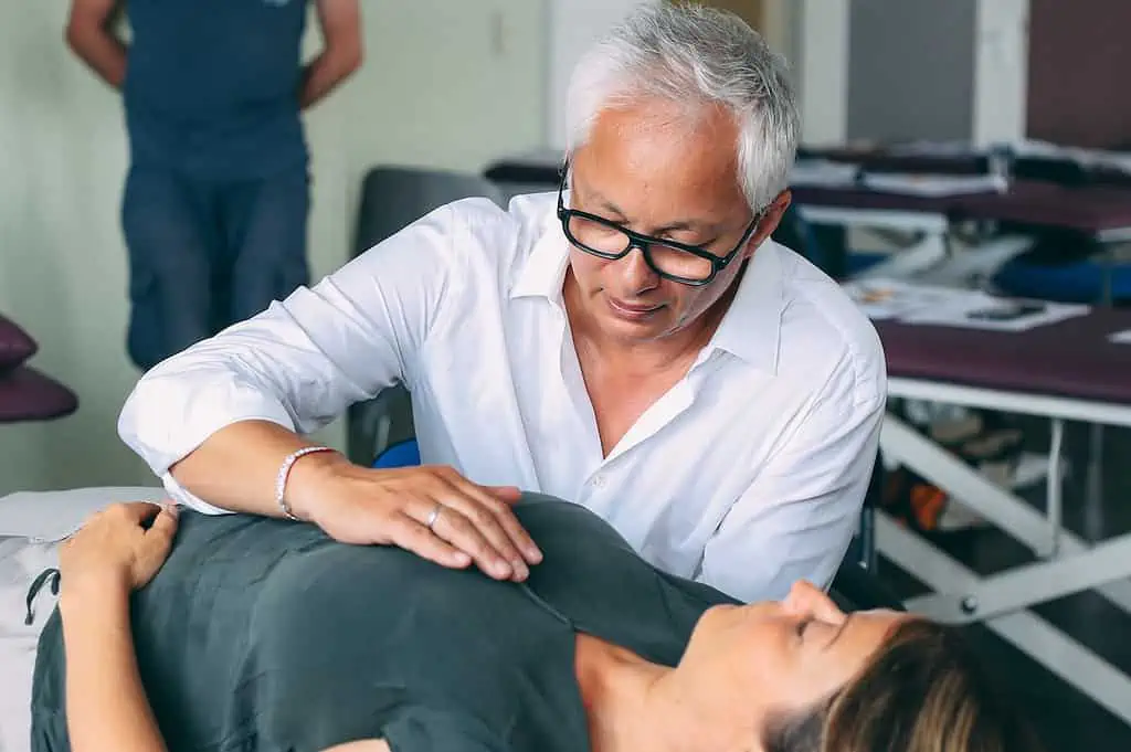 Ein Mann führt Osteopathen-Hamburg-Techniken am Bauch einer Frau durch.
