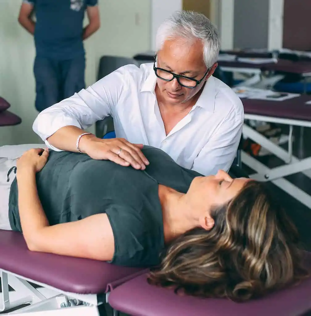 Eine Frau wird von einem Arzt für Kinderosteopathie untersucht.