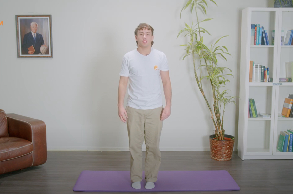 Un homme s'entraîne à trembler pour lutter contre le stress sur un tapis de yoga dans son salon.